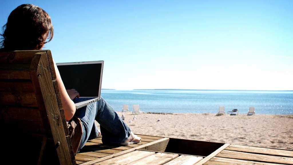 A person using a laptop to run a dropshipping business from a beach