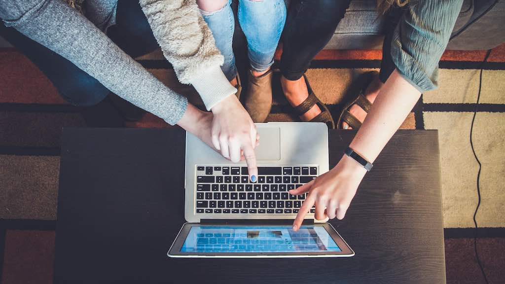 Image of several people pointing at a laptop screen.